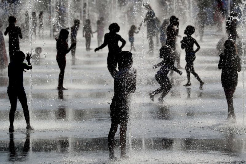 Children play under water jets in a fountain as they cool off during a heatwave in Nice on June 26, 2019. - Forecasters say Europeans will feel sizzling heat this week with temperatures soaring as high as 40 degrees Celsius (104 degrees Fahrenheit) in an "unprecedented" June heatwave hitting much of Western Europe. (Photo by VALERY HACHE / AFP)